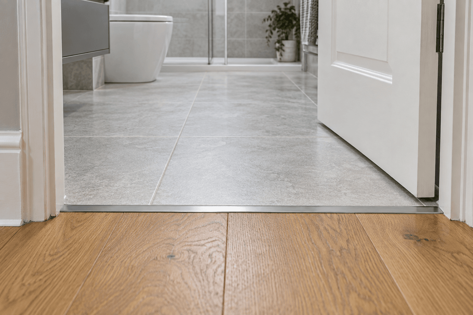 Illustration of flooring and carpentry details: an open door above the threshold between wood-effect boards and bathroom tiles.