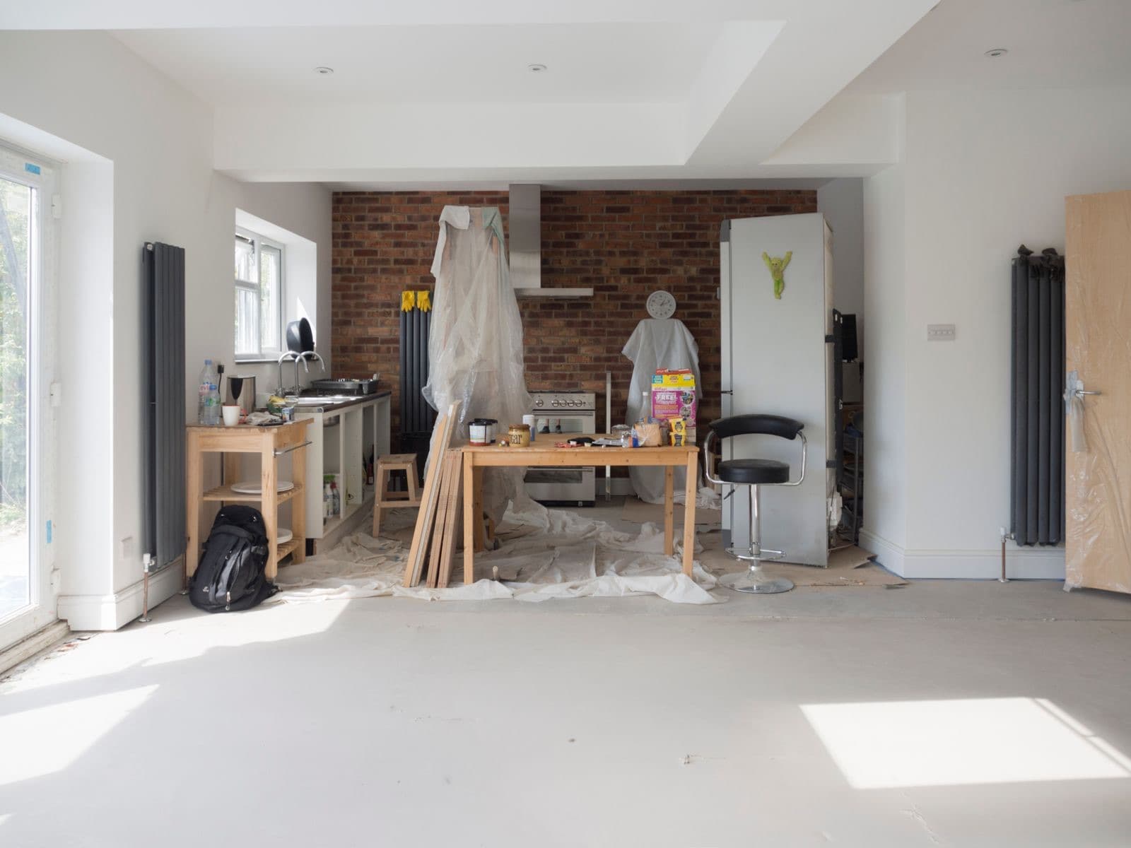 Stock photograph of a kitchen renovation interior with protected surfaces, decorating materials and unfinished flooring.
